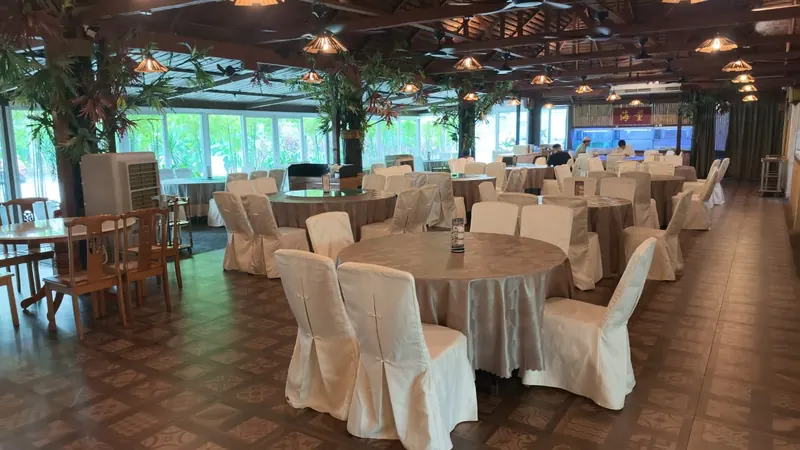 Main hall with round banquet tables, white chair covers and glass walls onto the garden